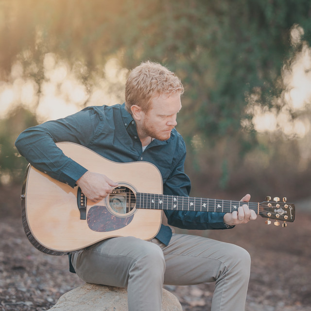 Sean Tobin playing acoustic guitar outdoors